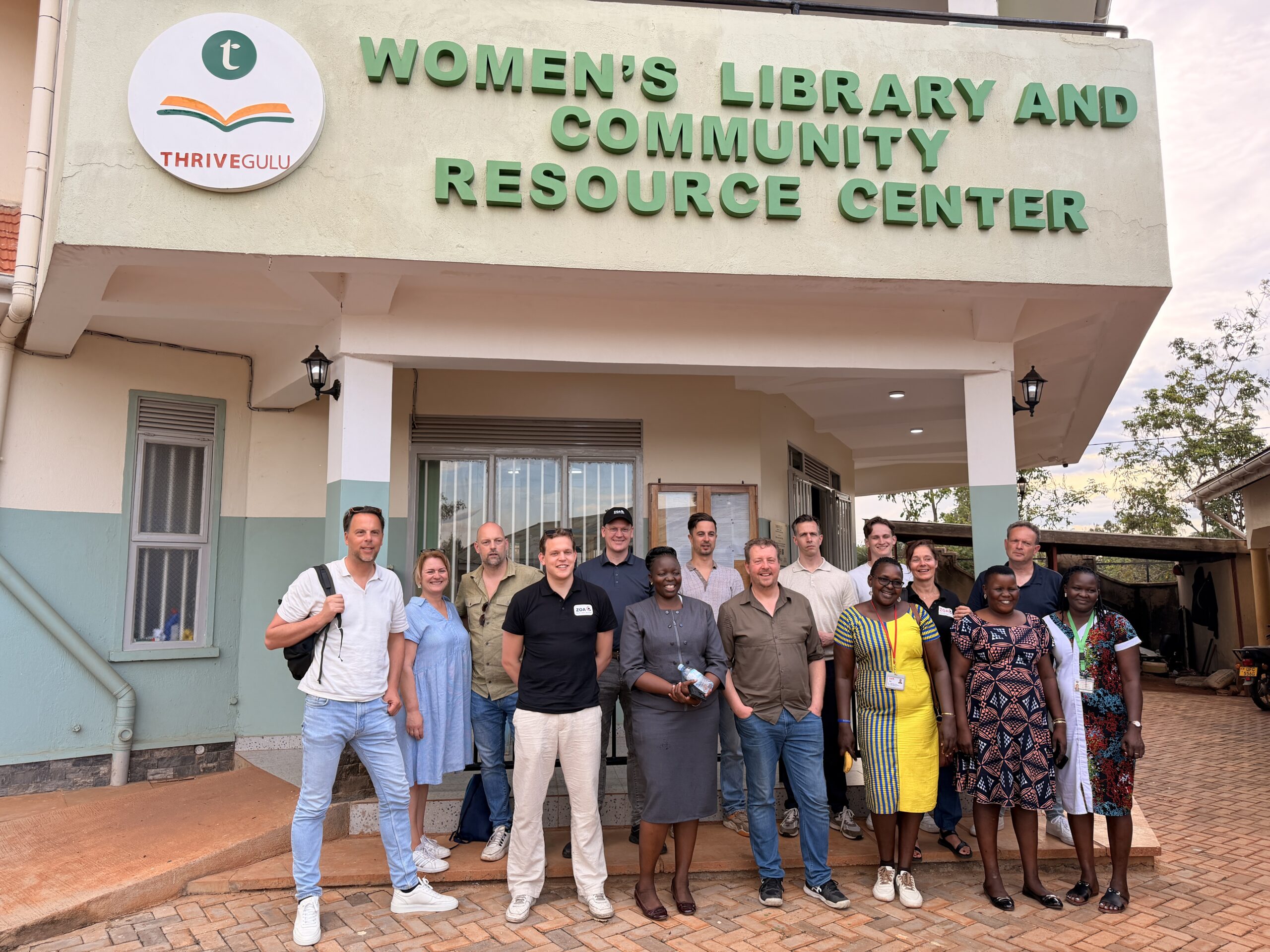 Group of people posing outside a building with a sign reading "Women’s Library and Community Resource Center."